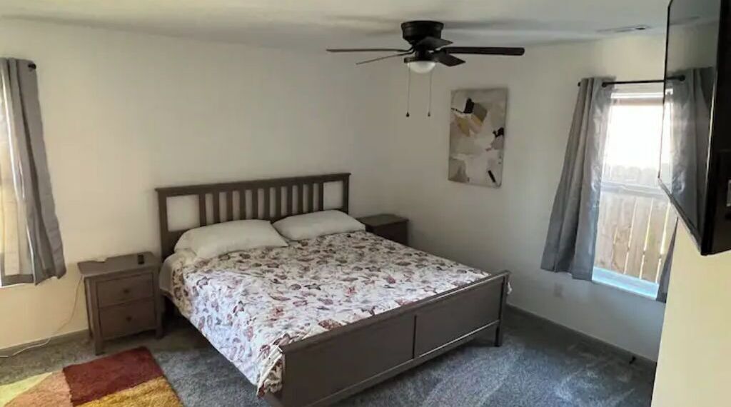 Ein Schlafzimmer mit Bett, Nachttisch und Deckenventilator.