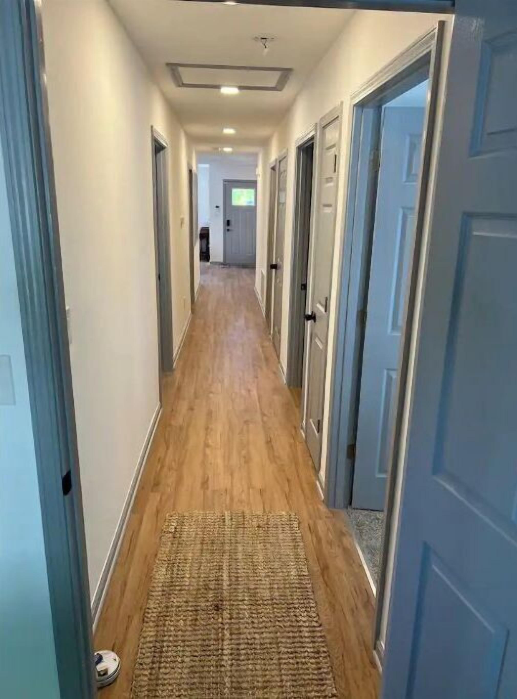 A hallway with wooden flooring and a rug at the entrance.