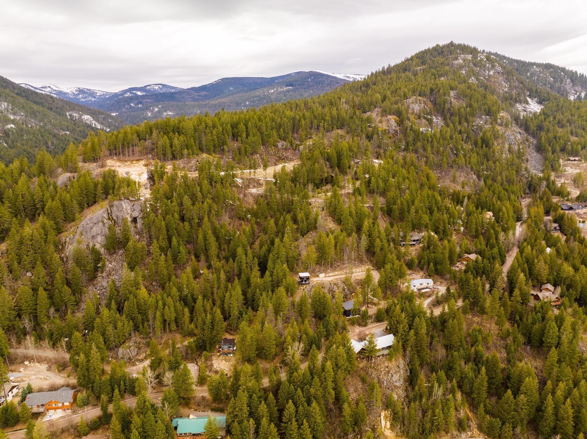 Un paisaje montañoso con casas dispersas rodeadas de bosques densos.