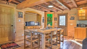 A rustic wooden interior with a dining table, chairs, a kitchen area, and a wooden ceiling. - Unadilla Cabin on 50 Acres + Fire Pit & Creek (Unadilla)