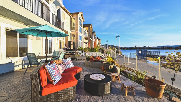 Une terrasse extérieure avec des meubles en osier, une table et un grand parasol.