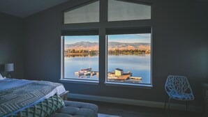 Une chambre avec une grande fenêtre donnant sur un lac et des montagnes.
