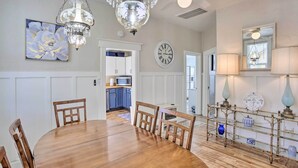 A dining area with a wooden table and chairs, a chandelier, a clock, and a kitchen in the background. - Mountain-View Lead Home w/ Patio + Fire Pit! (Lead)