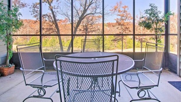 A patio with a round table and four metal chairs, overlooking a scenic view of trees and hills. - Cozy Condo w/ Nature Views: Branson Getaway (Branson West)