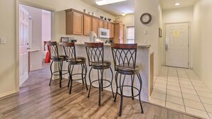 A kitchen with wooden cabinets, a microwave, and a bar stool area. - Cozy Condo w/ Nature Views: Branson Getaway (Branson West)