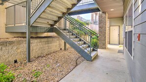 A covered outdoor staircase leading to a building entrance, with a brick wall and gravel ground. - Cozy Condo w/ Nature Views: Branson Getaway (Branson West)