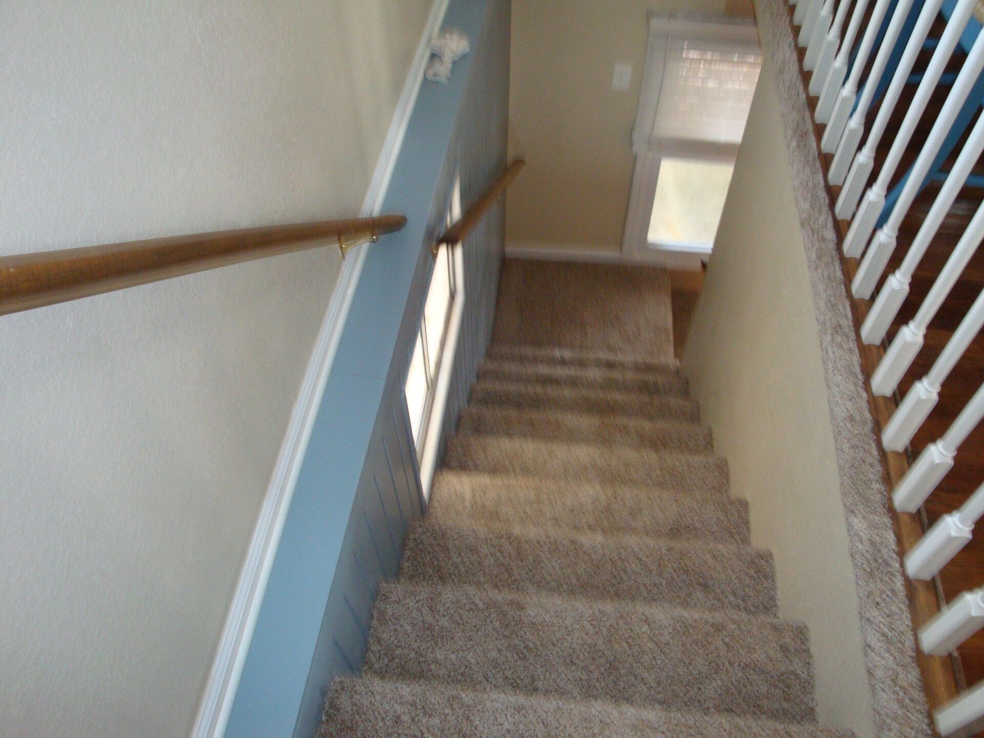 A carpeted staircase with wooden handrails and white balusters.