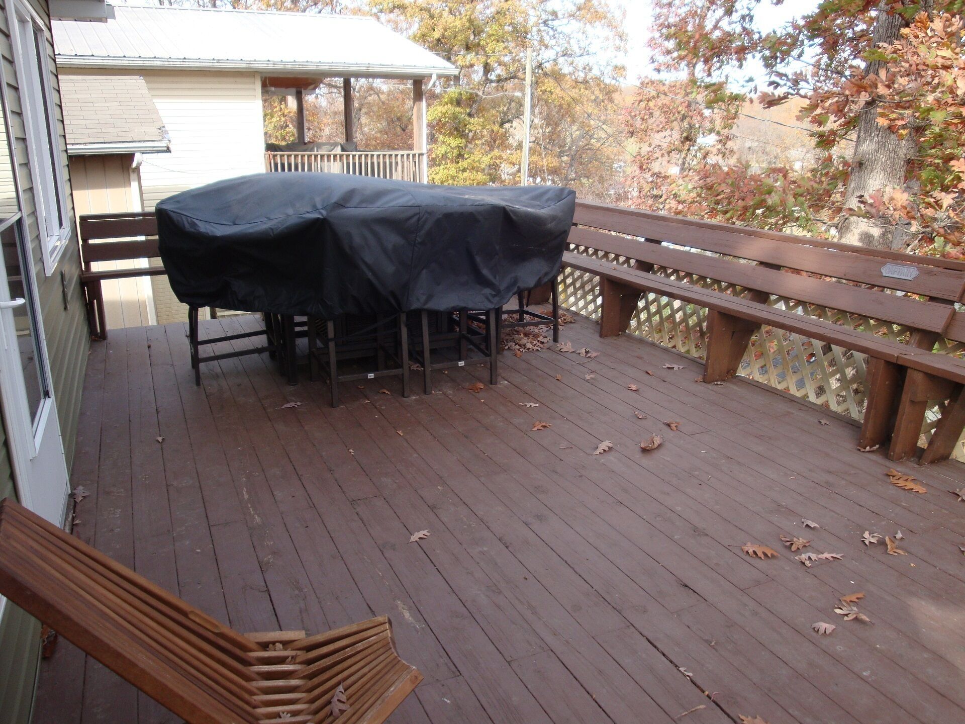 Una terraza de madera con una parrilla cubierta y un banco.