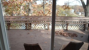 A wooden deck with two chairs and a bench, surrounded by a lattice fence, with fallen leaves on the ground. - Charming Lake View Cabin Retreat Near Captain Ron's Resort, Lake of the Ozarks (Sunrise Beach)
