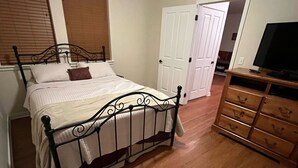 Un dormitorio con una cama, cómoda de madera y televisor.