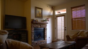 Una sala de estar con chimenea, televisor y muebles de cuero.