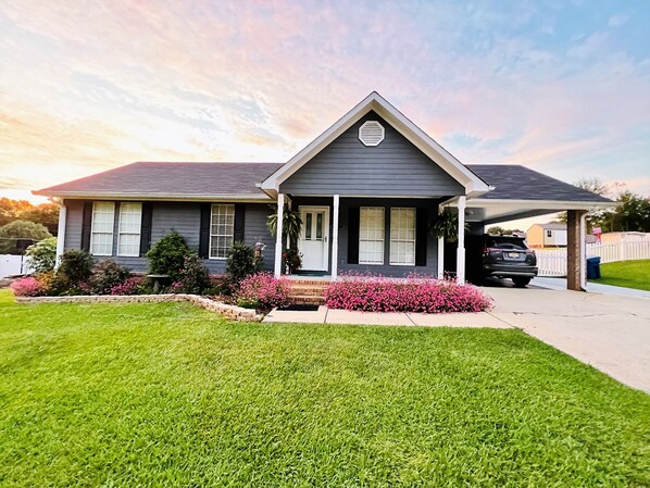 A residential house with a front porch, a garage, and a well-maintained lawn.
