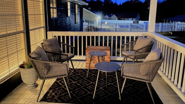 A covered porch with wicker chairs, a small table, and a hanging light fixture. - Country Living in Oxford (Oxford)