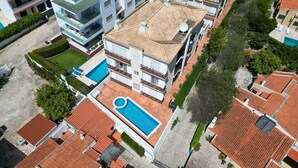 Ein mehrstöckiges Gebäude mit Pool auf dem Dach, Balkonen und einem Garten.