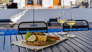 A dining table with a cheese platter, two glasses of white wine, and a pear. - Sanders White Mountains - Vibrant Villa With Pool (Tremithousa)