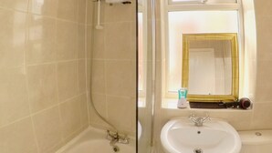 Un bagno con una vasca, un lavandino e una finestra con uno specchio.
