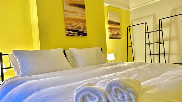 Una camera d'albergo con un letto, cuscini, una lampada e un quadro appeso al muro.