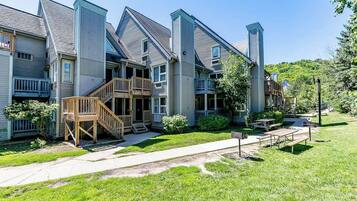 A row of multi-story buildings with balconies, a wooden staircase, and a picnic area.