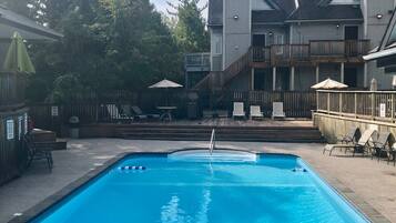 Relax by the rectangular pool surrounded by lounge chairs and umbrellas on a spacious deck.