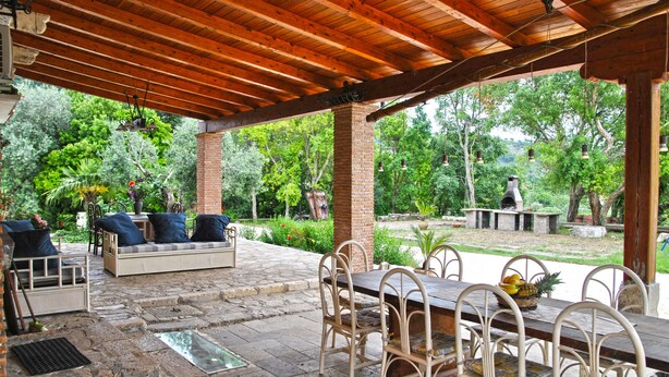 A covered patio with a wooden ceiling, outdoor seating, and a dining area with a table and chairs. - Meridiana Holiday House With Shared Swimming Pool (Itri)