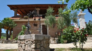 A stone fountain with a metal sculpture, surrounded by potted plants and red roses. - Meridiana Holiday House With Shared Swimming Pool (Itri)