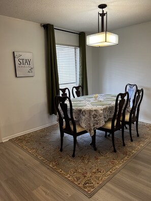 Cozy dining area with a round table for four, surrounded by cushioned chairs and a decorative rug.
