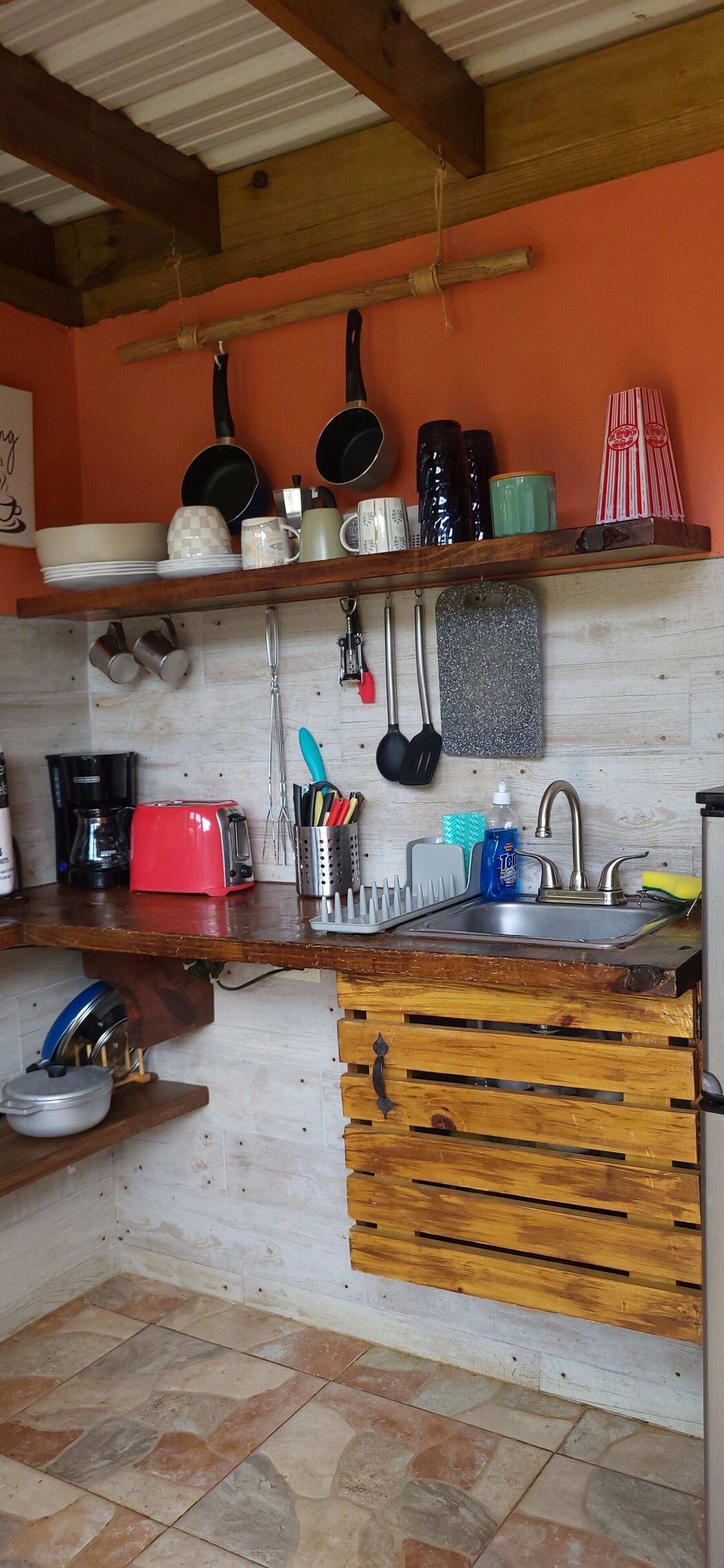 A kitchen with a wooden countertop, a sink, and various kitchen utensils and appliances.