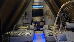 A cozy attic bedroom with two beds, a TV, and a hanging chair. - A unique way to camp in luxury (Aguadilla Pueblo)