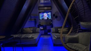 A cozy attic room with a television, two sofas, a dining table, and a hanging chair. - A unique way to camp in luxury (Aguadilla Pueblo)