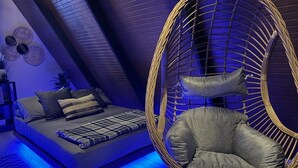 A modern bedroom with a bed, a wicker chair, and a blue-lit floor. - A unique way to camp in luxury (Aguadilla Pueblo)