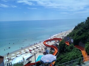 A beach with a water slide, umbrellas, and a pool. - Silver Beach B16 Apartment (Byala)