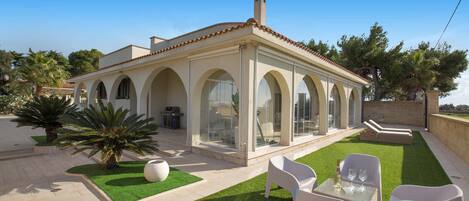 A modern house with a patio, outdoor seating, and a swimming pool.