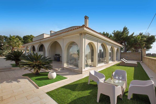 Uma casa moderna com um pátio, área de estar externa e piscina.