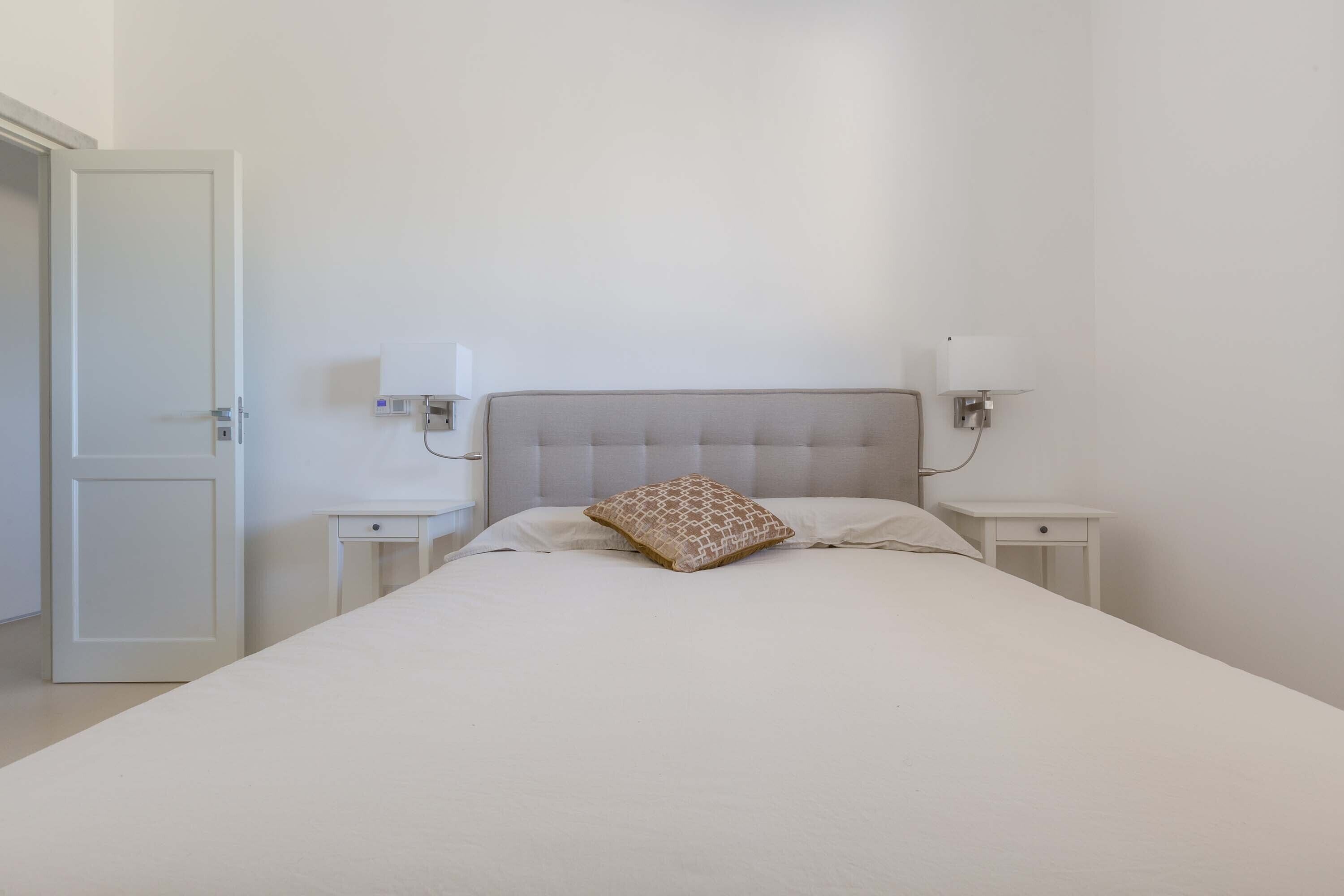 A minimalist bedroom with a single bed, two bedside tables, and a nightstand.