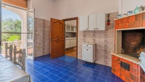 A kitchen with blue tiles, a wooden door, cabinets, and a tiled fireplace. - 2929 Villa Garden Rose by Barbarhouse (Porto Cesareo)