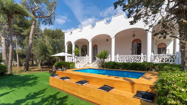 A poolside area with a wooden deck, a pool, and white columns. - 2929 Villa Garden Rose by Barbarhouse (Porto Cesareo)