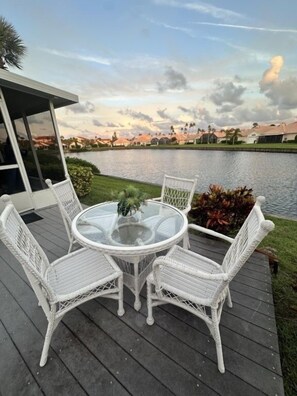 A deck with a glass table and wicker chairs overlooking a body of water. - Casa Bella At Sea Place New 3 Bedroom Home by RedAwning (St. Augustine)