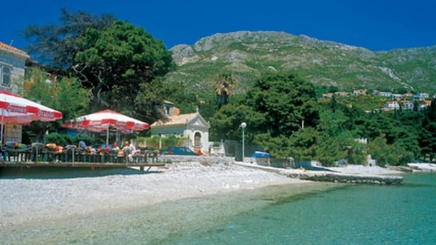A beach with clear turquoise water, a small kiosk, and a hill in the background. - Apartments & Rooms Jokovic (Zupa dubrovacka)