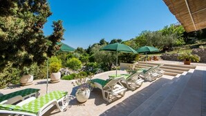An outdoor seating area with lounge chairs and tables, surrounded by potted plants and trees. - Apartments & Rooms Jokovic (Zupa dubrovacka)