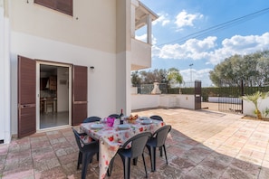 Une terrasse extérieure avec une table dressée pour les repas, un espace abrité et une vue sur le paysage environnant.