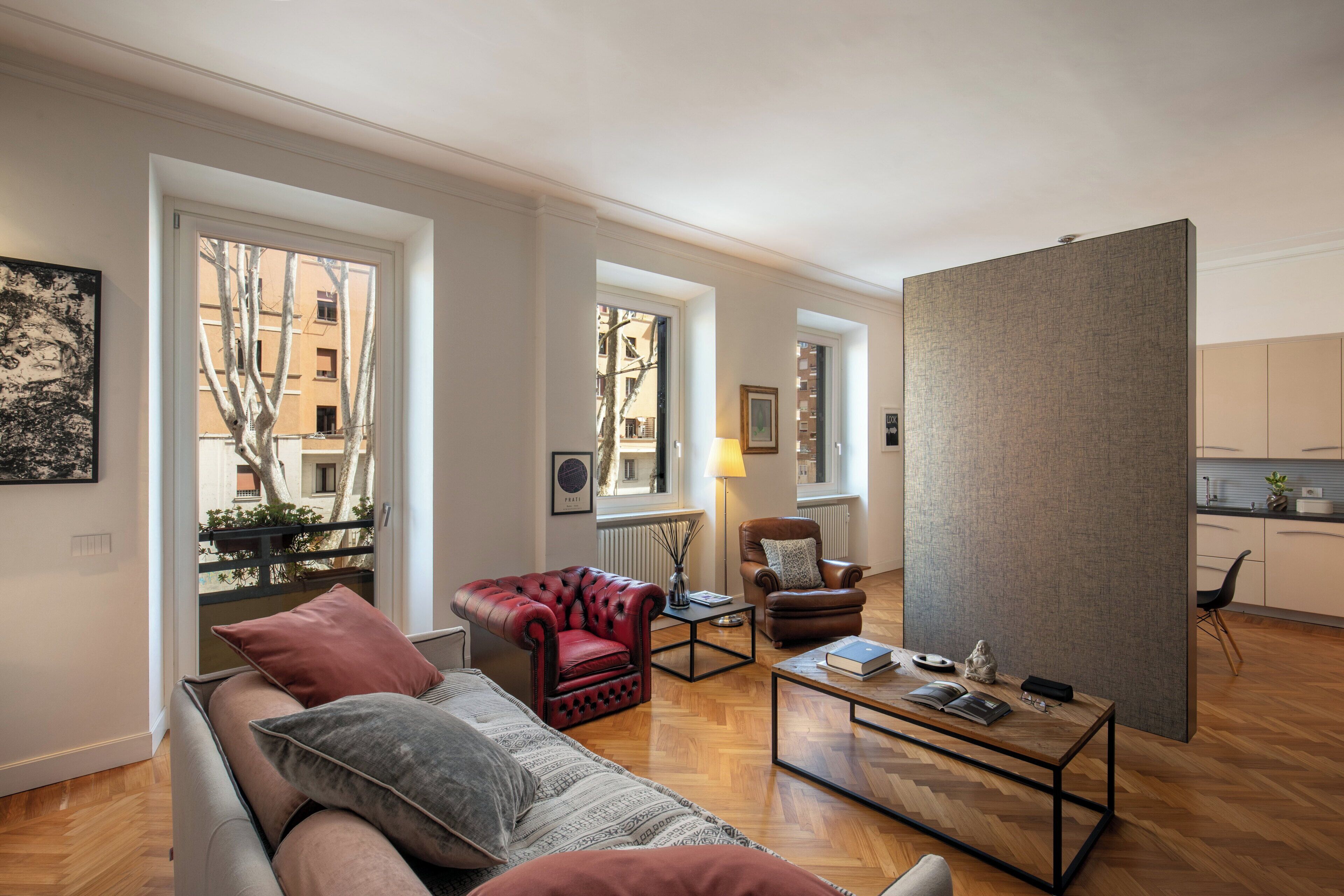 A modern living room with a sofa, armchairs, a coffee table, and a view of the outside.