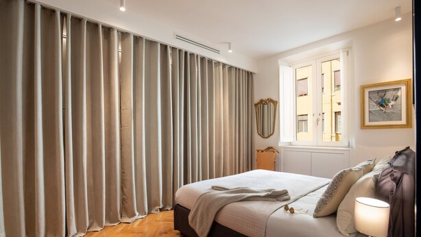 A bedroom with a bed, curtains, a window, a bedside table, and a lamp. - Wonderful 1 Bedroom Apartament in the City Center (Rome)