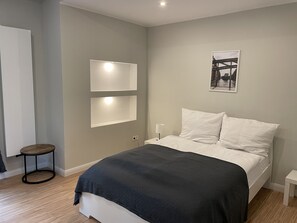 A modern bedroom with a bed, bedside tables, and wall-mounted lights. - Ahoi Hostel (Hamburg)