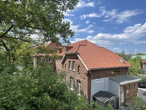 A traditional brick building with a red-tiled roof, a sign reading "AHOI HOSTEL," and a small attached structure with a metal roof.
