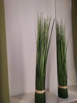 A room with a white wall and a shelf holding a bundle of green grass tied with a brown band. - Room in Guest Room - Pension Forelle - Doppelzimmer (Forbach)