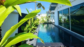 Una casa moderna con piscina, rodeada de exuberante vegetación.