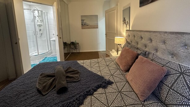 A bedroom with a bed, a headboard, a bedside table, a lamp, and a shower area. - Gorgeous 4 Bedrooms, 5-baths House Central London (London)