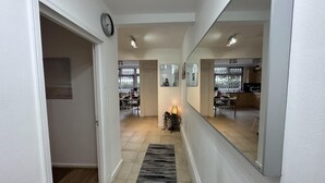 A hallway with a clock, a rug, and a mirror reflecting a kitchen area. - Gorgeous 4 Bedrooms, 5-baths House Central London (London)