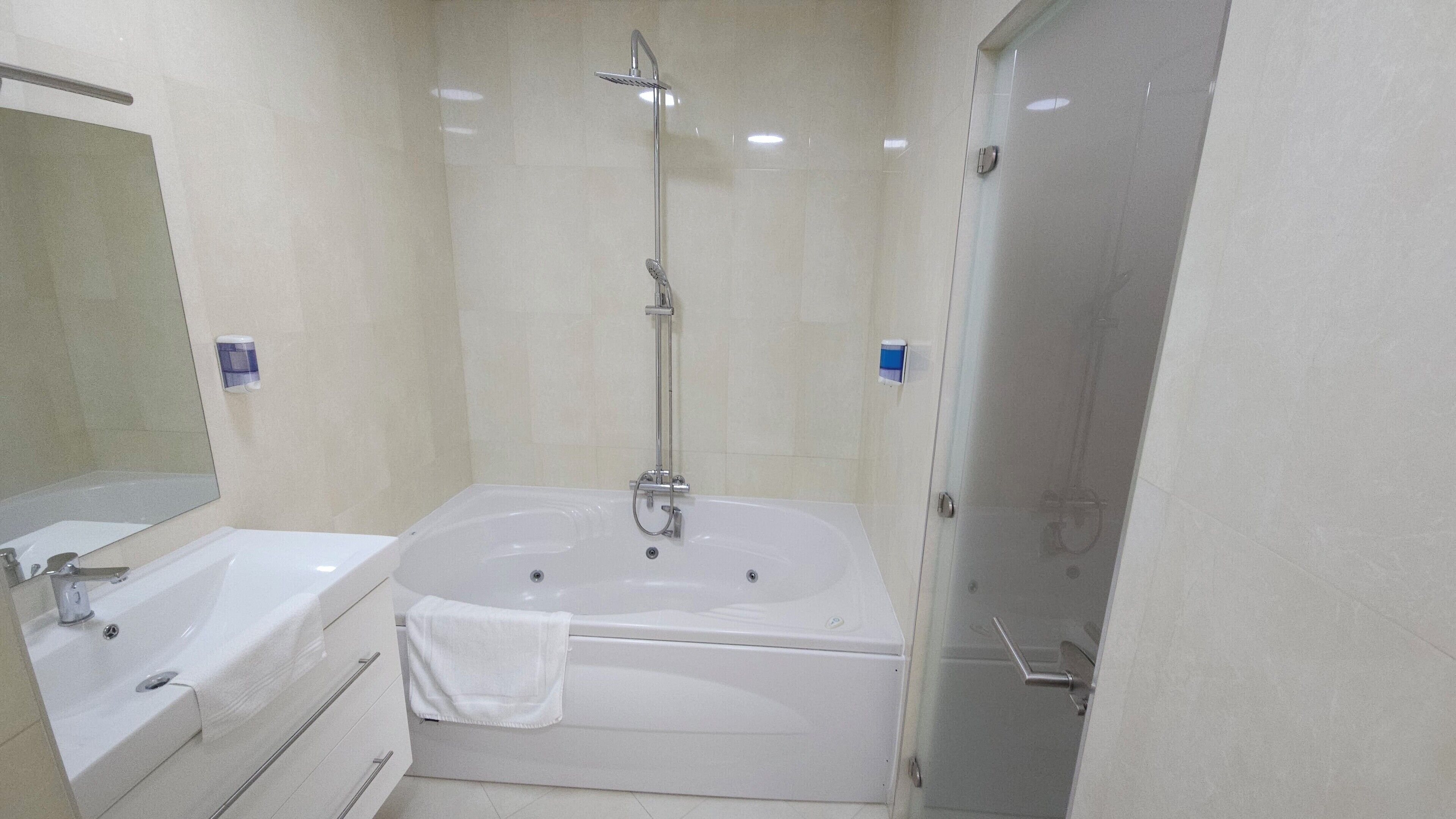 A modern bathroom with a bathtub, a shower, and a sink.