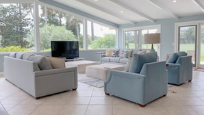 Amplia sala de estar con televisor grande, asientos cómodos y ventanas grandes con vistas al exterior.